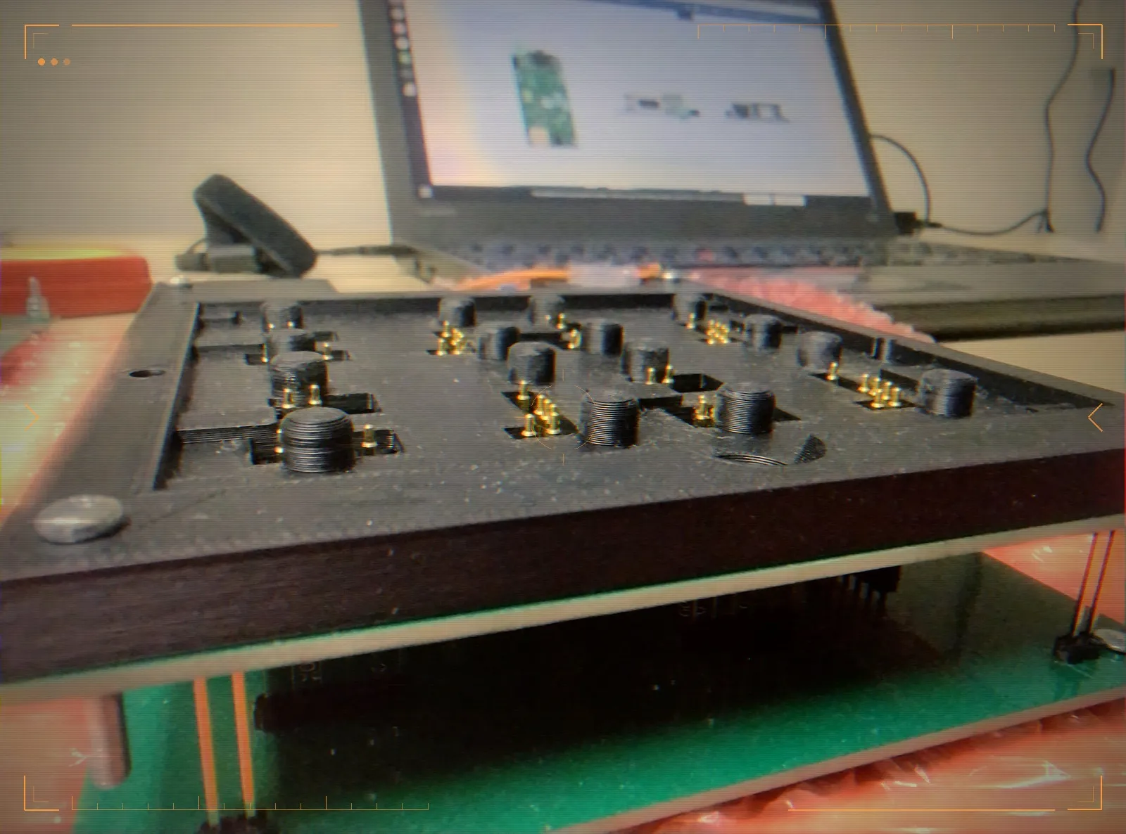 Close-up of the fixture bed — a 3D-printed plate with gold pogo-pin contacts